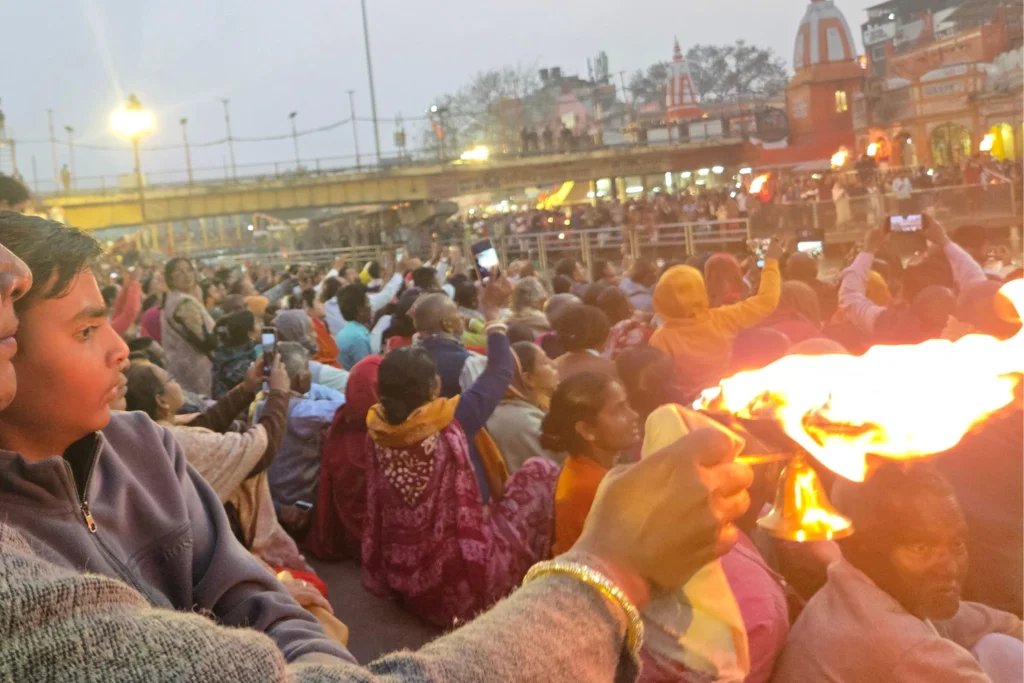 Devotees holding deepak during Ganga Aarti at Har Ki Pauri, Haridwar — crowd visible with mobile phones capturing the ceremony